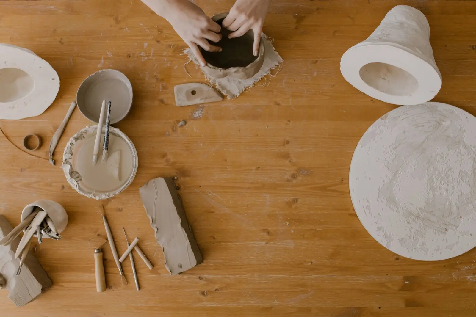 Klei en gereedschap op een houten werktafel, van bovenaf