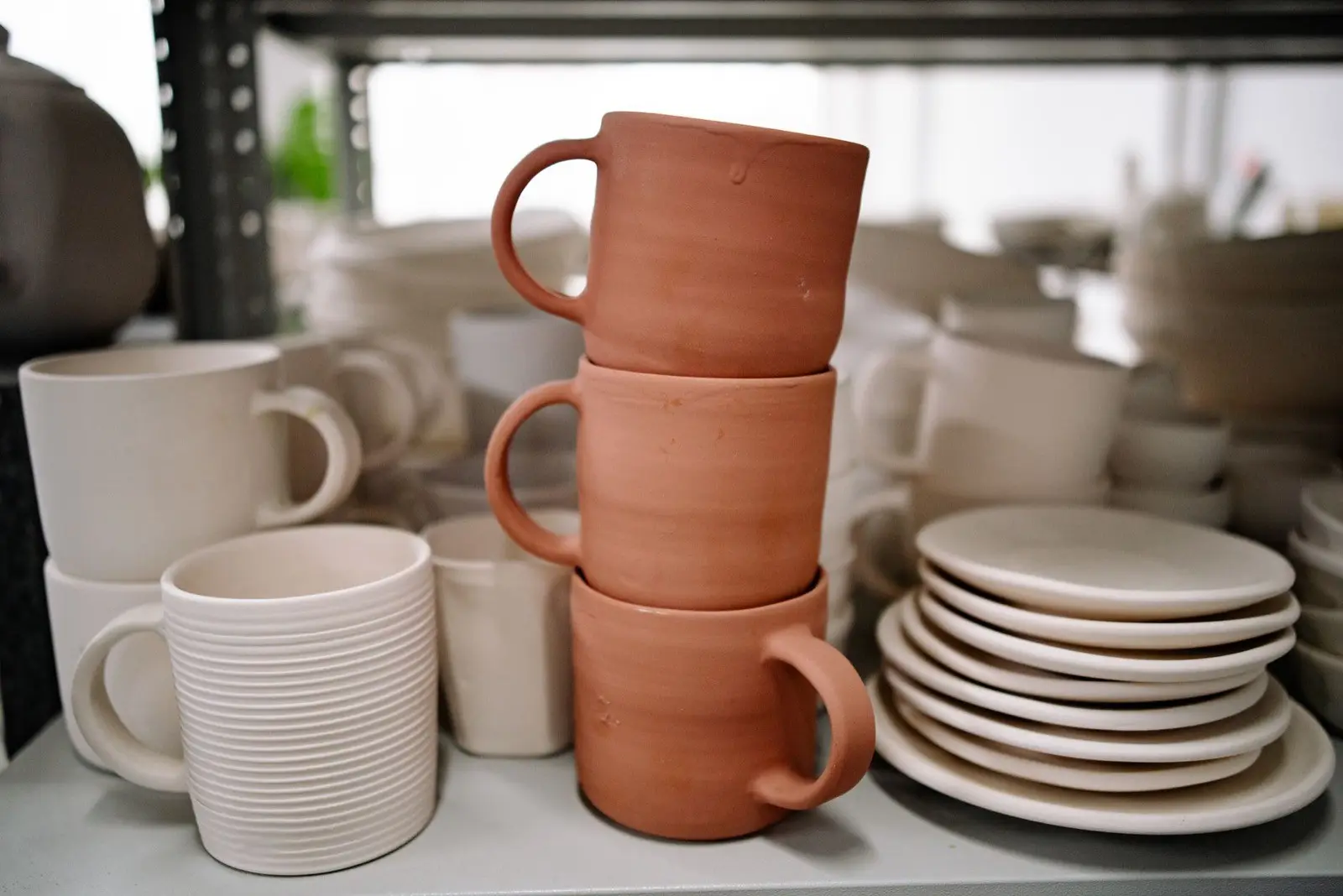 Gestapelde mokken van terracotta en witte klei